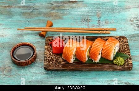 Primo piano: Un set di sei panini Philadelphia con salmone crudo serviti su un piatto di palma sul tavolo blu, vista dall'angolo di higgh Foto Stock