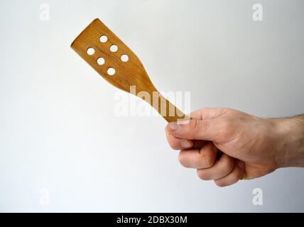 Mano dell'uomo con spatola di legno isolata su bianco Foto Stock