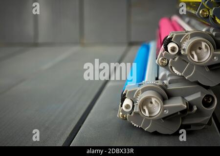 Vista laterale delle cartucce di inchiostro del toner per un laser da ufficio stampante su sfondo grigio in legno Foto Stock