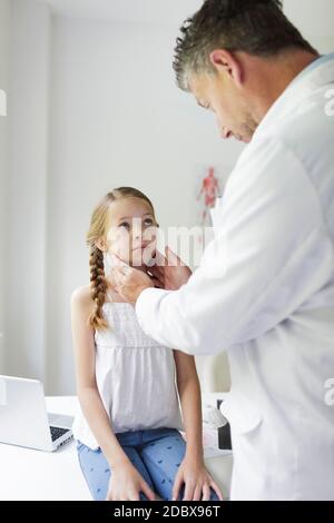 il medico maschile in camice bianco esamina giovane, bella ragazza nella sua pratica Foto Stock