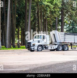 Potente Day Cab bianca grande carro semi-camion industriale scorrimento lungo le guide scarico semi-rimorchio poggiato su parcheggio dell'area di riposo nei vecchi fori Foto Stock