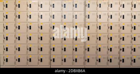 Armadietto beige con serratura e targhette gialle numerate nell'armadietto. Armadietto di sicurezza. Fila di armadietti con sportello chiuso a chiave Foto Stock