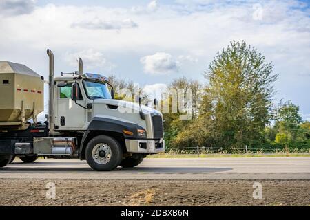 Potente Day Cab bianca grande carro semi-camion industriale scorrendo lungo le guide, scaricare il semirimorchio in esecuzione su autostrada fino al luogo di lavoro dest Foto Stock