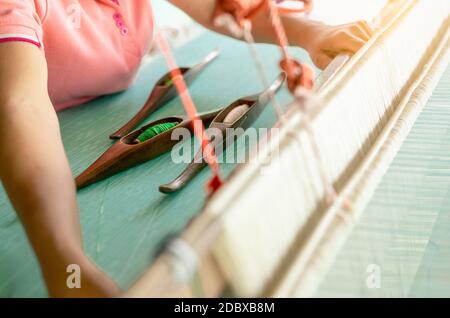 Donna al lavoro su macchina di tessitura per la tessitura di tessuti fatti a mano. Tessitura di materie tessili. Utilizzando la tessitura a mano tradizionale telaio di tessitura su ciocche di cotone. O di materie tessili Foto Stock