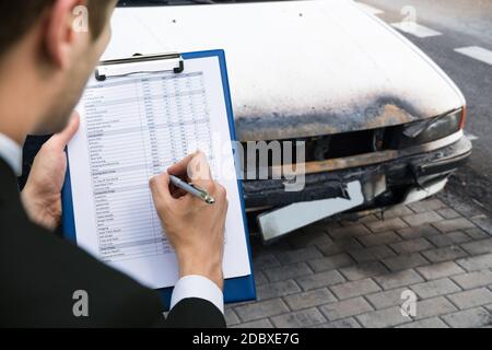 Agente di assicurazione che esamina l'automobile dopo l'incidente di fuoco Foto Stock