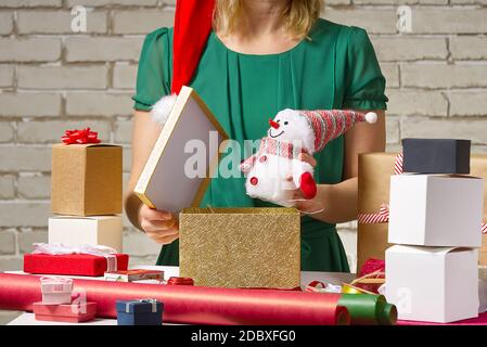 Confezione regalo per Natale e Capodanno. Mani fatte a mano. Ragazza con nastro regalo, spago, nastro e presente avvolto Foto Stock