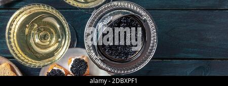 Cucina gourmet, stile vintage, panorama. Caviale e champagne, girato dall'alto con spazio per la copia su uno sfondo di legno blu scuro Foto Stock