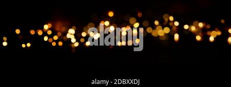 Sfondo nero con effetti di luce dorata. Sfondo orizzontale con effetti bokeh sfocati per il periodo natalizio. Concetto di occasione speciale con spazio per Foto Stock