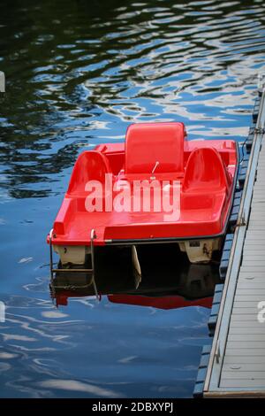 Un pedalò rosso giace sul molo e attende i clienti. Foto Stock