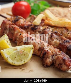 Souvlaki cibo greco. Spiedini di carne alla griglia serviti con patate fritte, pane pita e limone, vista closeup. Turco shish kebab, shashlik Foto Stock