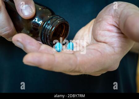 uomo versando 2 pillole da prescrizione pillola bottiglia nel suo mano Foto Stock