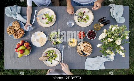 Cena per famiglie all'aperto. Cena in famiglia con insalata biologica e formaggio su un tavolo alla moda in stile scandinavo in giardino. Sana estetica cibo bello, su Foto Stock