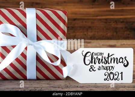 Un regalo di Natale con etichetta con calligrafia inglese buon Natale e UN felice 2021. Avvolgimento della carta con un arco Foto Stock