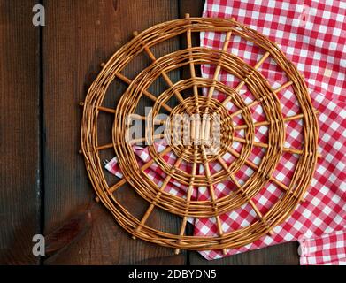 supporto rotondo in vimini per pentole su un tavolo di legno marrone, vista dall'alto Foto Stock