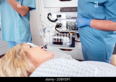 Paziente donna in ospedale che guarda infermieri che si preparano per l'intervento chirurgico Foto Stock