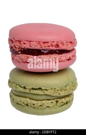 Dolci, dessert e dolci. Primo piano di un macaron rosso lampone francese e di un macaron verde pistacchio isolato su sfondo bianco. Foto macro Foto Stock