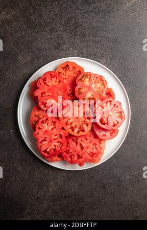 Bistecca rossa a fette tomatoe su tavola nera. Vista dall'alto. Foto Stock