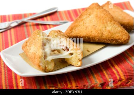 Un piatto tipico della cucina romana in Italia chiamato mozzarella in carrozza, pane in pangrattato fritto e con mozzarella a fette sul fondo di un rosso Foto Stock