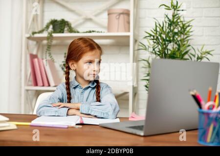 felice bambina che usa il laptop per studiare il sistema di apprendimento online. lezione online a casa. bambino ascolta attentamente l'insegnante. Foto Stock