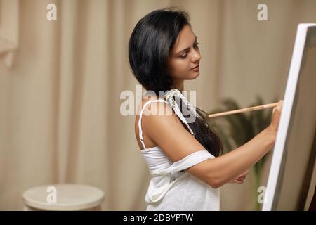 ritratto di calma artista femminile di fronte a easel. Donna pittura in studio d'arte Foto Stock