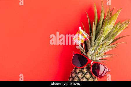 Festeggia l'estate concetto di Pineapple Day, vista dall'alto piatto di divertente ananas indossare occhiali da sole rossi, studio girato isolato su sfondo rosso, Holiday summ Foto Stock