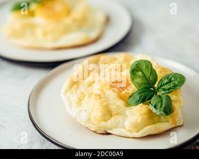 Uova di nuvola soffici. Cibo alla moda - forno cuocere uova strapazzate con albume d'uovo montato e tuorlo intero sul piatto Foto Stock