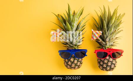 Festeggia l'estate concetto di Pineapple Day, vista dall'alto piatto di divertenti due ananas in occhiali da sole, studio girato isolato su sfondo giallo, Holiday su Foto Stock