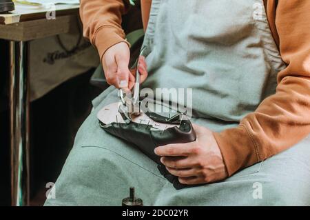 Primo piano della realizzazione di scarpe da calzolaio utilizzando gli attrezzi in officina Foto Stock