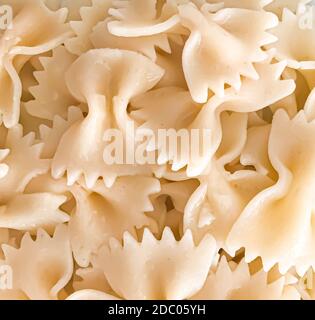 Primo piano di fondo di pasta di farfalle. Le farfalle sono un tipo di pasta/noodle comunemente noto come pasta con cravatta o pasta con farfalla. Foto Stock