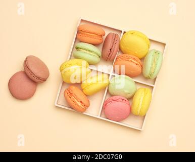 scatola di legno e biscotti macaron multicolore al forno su sfondo beige, vista dall'alto Foto Stock