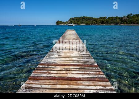 Vecchio e indossato molo con acque turchesi visto vicino Rovigno, Croazia Foto Stock