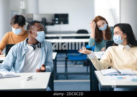 Studenti internazionali che indossano maschere mediche e parlano Foto Stock