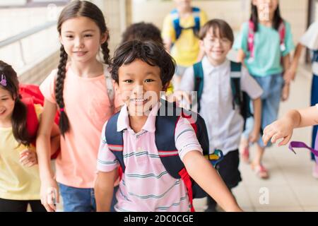 Gruppo felice di bambini della scuola elementare che corrono in avanti Foto Stock