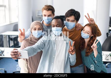 Studenti internazionali che indossano maschere mediche che prendono selfie Foto Stock