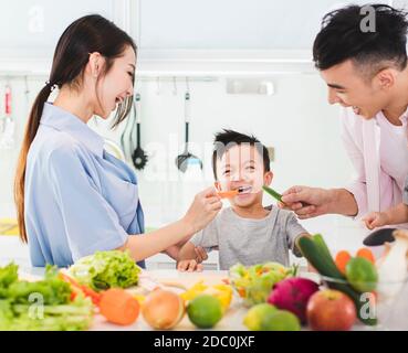 genitore che alimenta un pezzo di carota in cucina Foto Stock