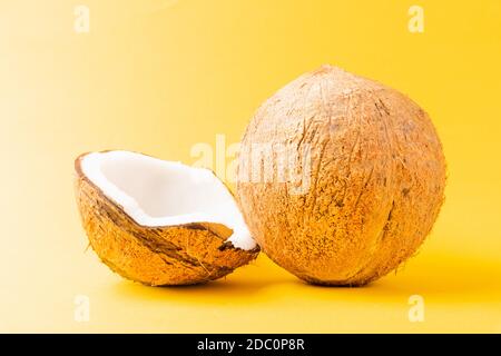 Happy Coconuts giorno concetto, fresco pieno cocco con mezzo cocco, studio girato isolato su sfondo giallo Foto Stock