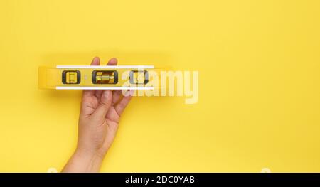 strumento di livello giallo in plastica con presa a mano femmina con capsule su sfondo giallo, spazio per la copia Foto Stock