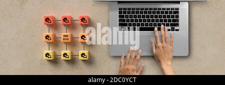 Cube griglia con message HOME OFFICE e consegnare un computer su sfondo cartaceo Foto Stock