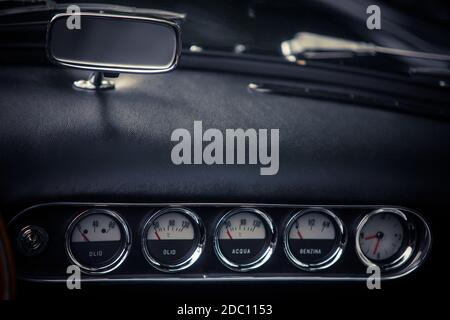 Immagine ravvicinata di un liquido di raffreddamento, un orologio e altri indicatori vari sul cruscotto di un'auto d'epoca. Foto Stock
