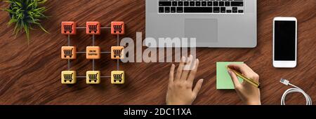 Cubo-griglia con messaggi ONLINE SHOPPING e i simboli del carrello e prendere appunti a mano su sfondo di legno Foto Stock