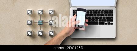 Cubo griglia con message HOME OFFICE e mano con smartphone su laptop su sfondo cartaceo Foto Stock