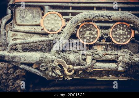 Primo piano di un'auto fuori strada, coperta di fango, con barra di carico e fari. Foto Stock