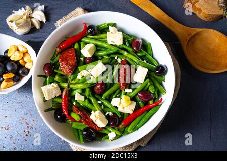 Insalata di fagioli verdi speziati con olive, formaggio feta e pomodori secchi Foto Stock