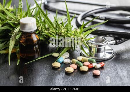 Boccioli di marijuana fiori di cannabis, stetoscopio, pillole e olio su tavola nera. Foto Stock
