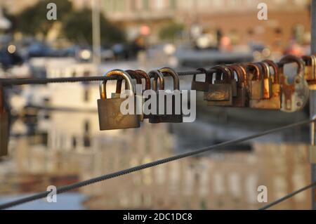 Lucchetti d'amore arrugginiti appesi su un filo di ferro sul mare background.Many lucchetti di amanti appesi su ringhiere ponte. Foto Stock
