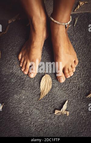 Benvenuto autunno sfondo. Closeup Concept Foto di una donna a piedi nudi piedi e foglie secche. Tema della stagione autunnale. Foto Stock