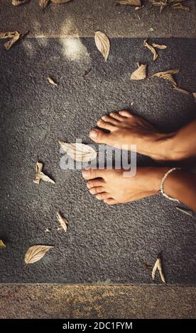 Benvenuto autunno sfondo. Closeup Concept Foto di una donna a piedi nudi piedi e foglie secche. Tema della stagione autunnale. L'estate è finita. Foto Stock