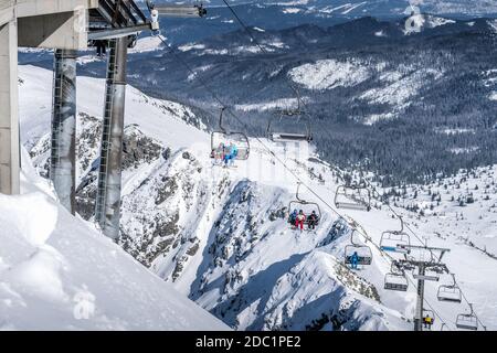 Sciatori e snowboarder salendo sulle piste da sci di Kasprowy Wierch su un impianto di risalita. Vacanze invernali in alta montagna Tatra, Polonia Foto Stock