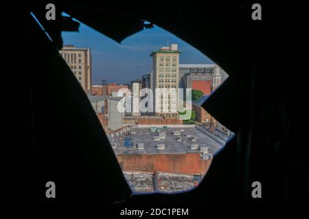 Una skyline della città con un aereo che attraversa un foro affilato In un muro Foto Stock