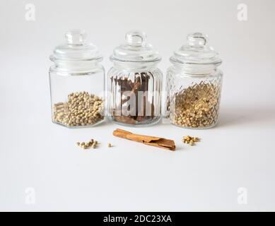 Spezie diverse in piccole bottiglie isolate su sfondo bianco Foto Stock